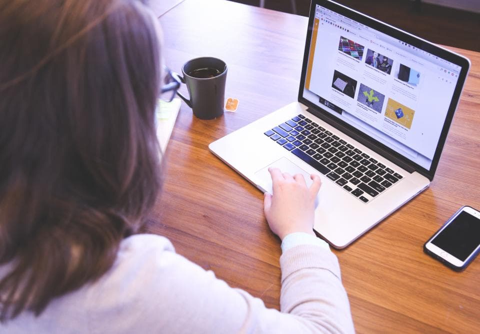 A person working on a laptop at a wooden desk