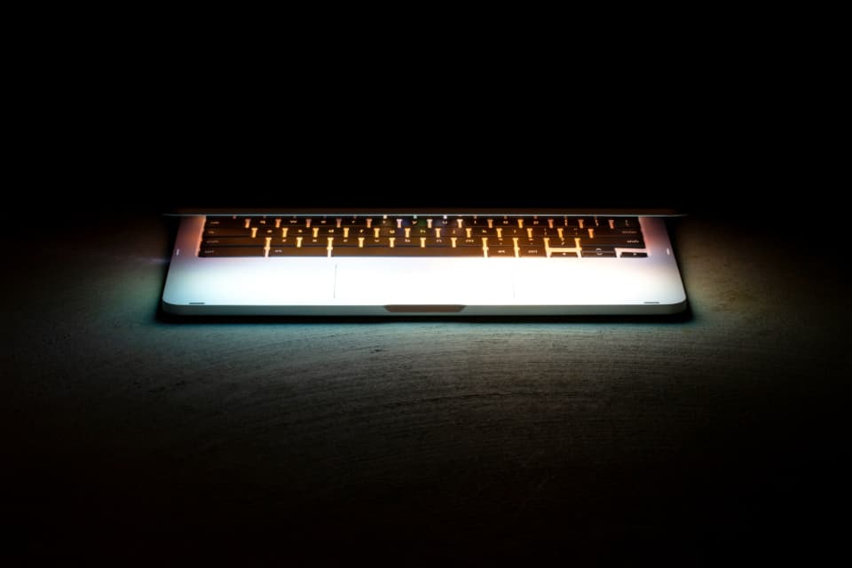 A laptop keyboard glowing softly in a dark room